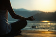 © Microgen - Meditation by the lake. Silhouette of a young woman meditating by the lake at sunset