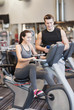 © Syda Productions - happy woman with trainer on exercise bike in gym