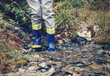 Child legs in gum boots into the forest creek