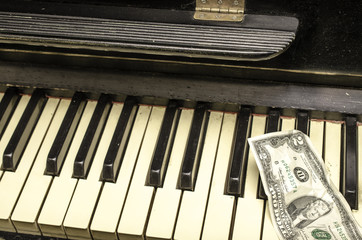 Keys of old piano and banknote two dollars.