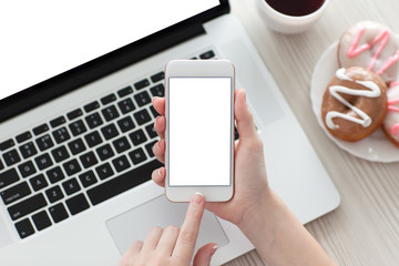 female hand holding white phone with isolated screen and laptop