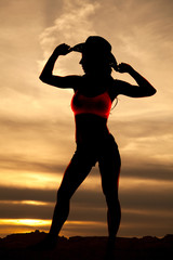 Poster - Silhouette of cowgirl stand look side hands on hat