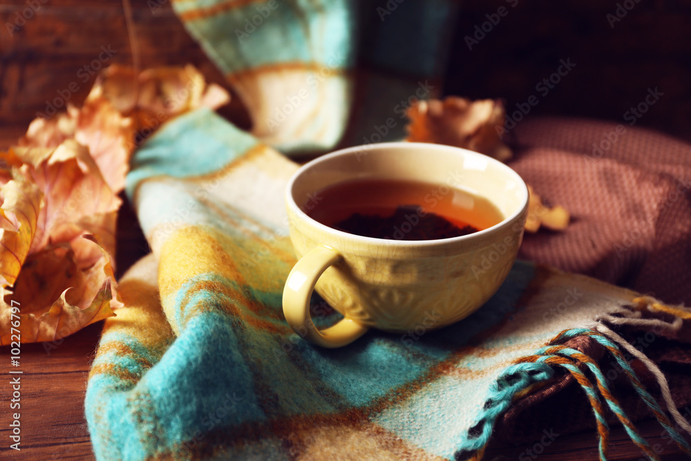 Cup of tea with autumn decor on wooden table.