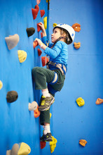 Little Boy Is Climbing On Blue Wall