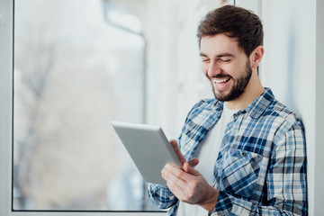 Smiling man playing on digital tablet