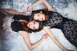 © cherry_d - Portrait of beautiful twins young women in gorgeous evening dresses lying on a snow