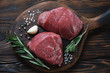Raw filet mignon steaks with seasonings, rustic wooden setting