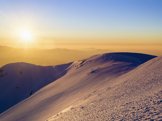 Wall Mural - Scenic view of the sunset in the winter mountains. Direct sunlight. Sun rays. Light reflected from the snow. Clear sky. Deep shadows. Ukraine