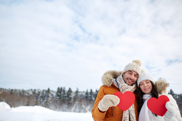 happy couple with red hearts over winter landscape