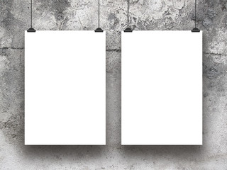 Close-up of two hanged paper sheet frames with clips on grey weathered concrete wall background