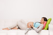 Pregnant happy smiling woman lying on a sofa and examining her belly. Mom Expecting Baby. Portrait of young beautiful mom expecting Baby. Pregnant Woman Belly. Maternity concept.