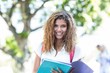 © WavebreakmediaMicro - Hip woman holding notebook and smiling at the camera