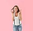 © goodluz - Trendy girl with suspenders moving on pink background