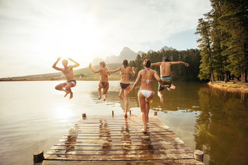 Young friends jumping into a lake