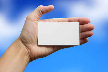 Hand holding white business card on blurred background