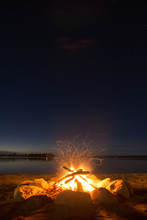 Sparking Camp Fire Beside Lake Under A Starry Sky