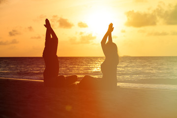 silhouette of couple doing yoga at sunset