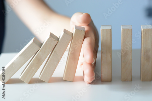 Fotografie, Obraz Stopping the domino effect concept with a business solution and intervention