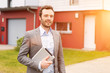Portrait of a young real estate agent in front of a house