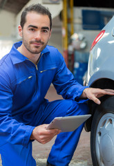 Wall Mural - Young attractive mechanic working on a car at the garage