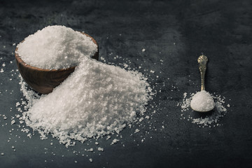 Salt. Coarse grained sea salt on granite - concrete  stone background with vintage spoon and wooden bowl.