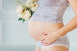 pregnant woman holding her belly and flowers