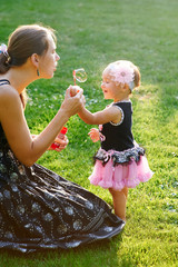 young mother and her little daughter playing on grass