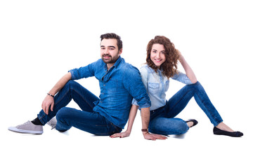 happy young couple sitting on the floor isolated on white