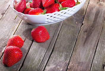 Part of a dish with strawberry and some fallen red berries on ol