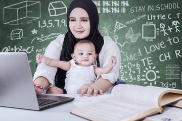 Busy teacher and baby using laptop in class