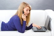 © ratmaner - Woman talking on mobile phone and using laptop lying on sofa, modern technology