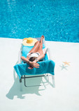 Fototapeta Natura - Woman in hat relaxation at swimming pool bed