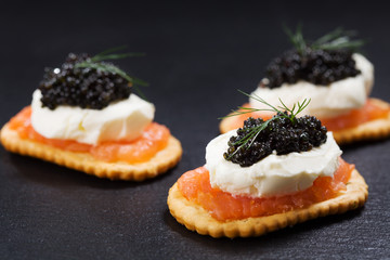 Black caviar served on crackers with salmon and cream cheese.