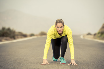 attractive blond sport woman ready to start running practice training race starting on asphalt road mountain landscape