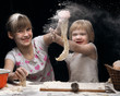 Children playing with flour. Children knead the dough. Girls funny soiled with flour. The kids meal and a table. Very fun game, children are happy 