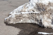 Melting dirty snowbank on asphalt