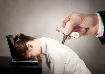 businesswoman with a key winder on her back sleeping on laptop