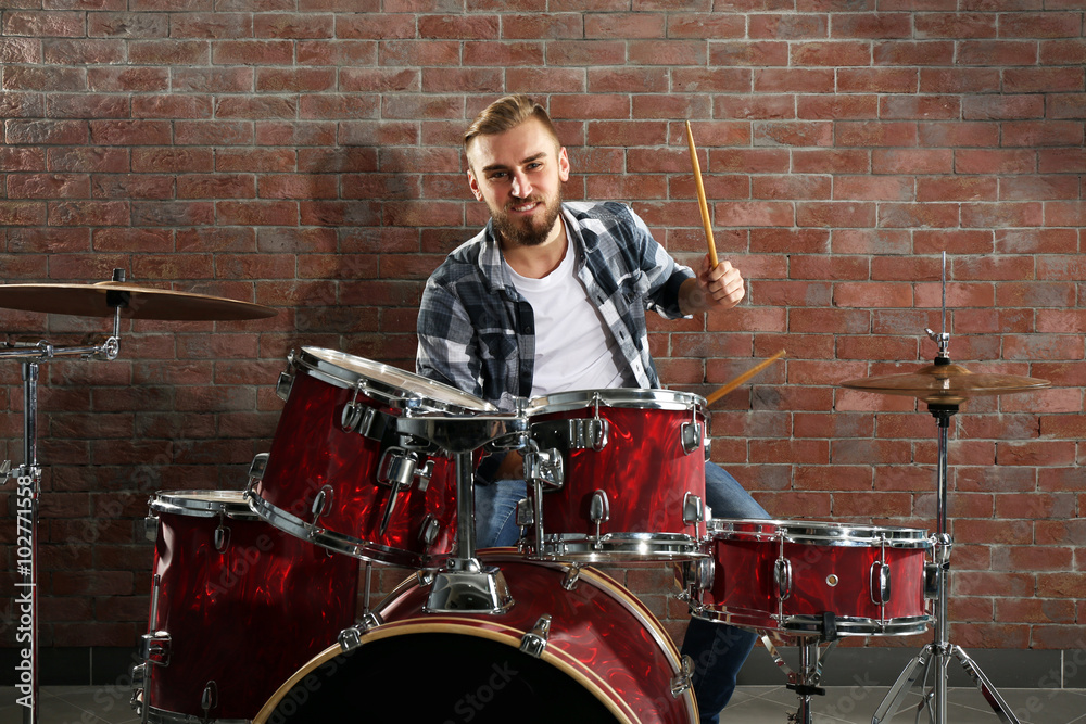 Musician playing the drums on brick wall background