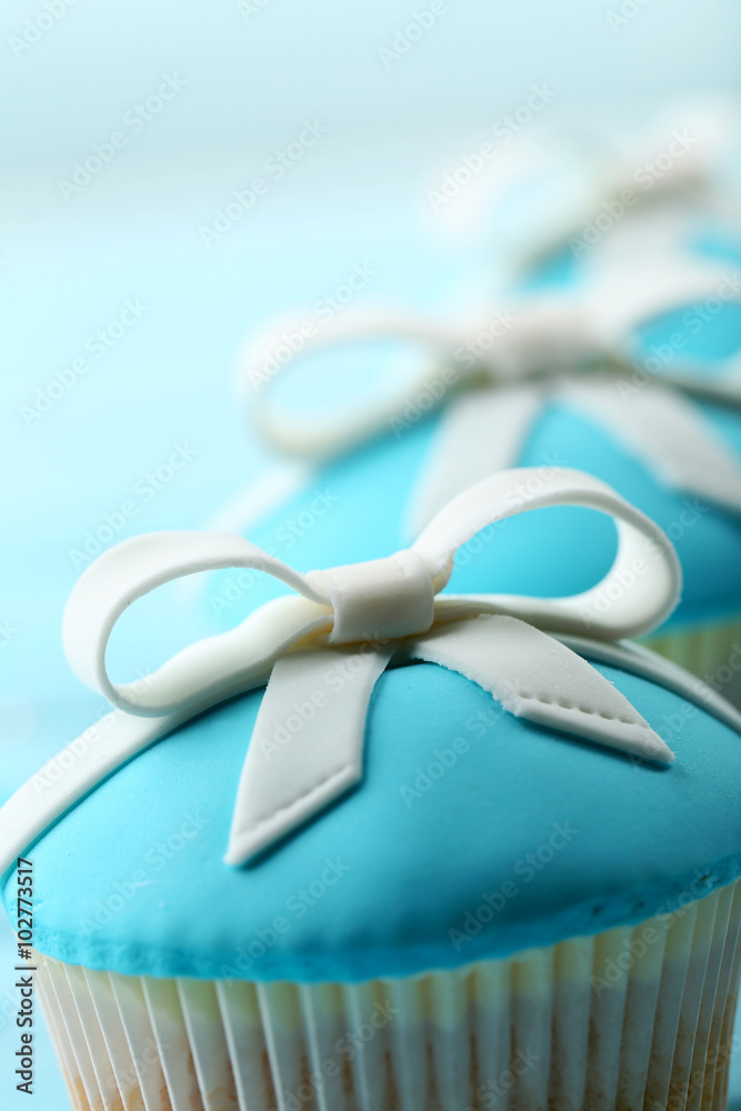 Tasty cupcakes with bow on color wooden background