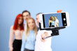 © Africa Studio - Young people making group photo with smart phone on blue wall background