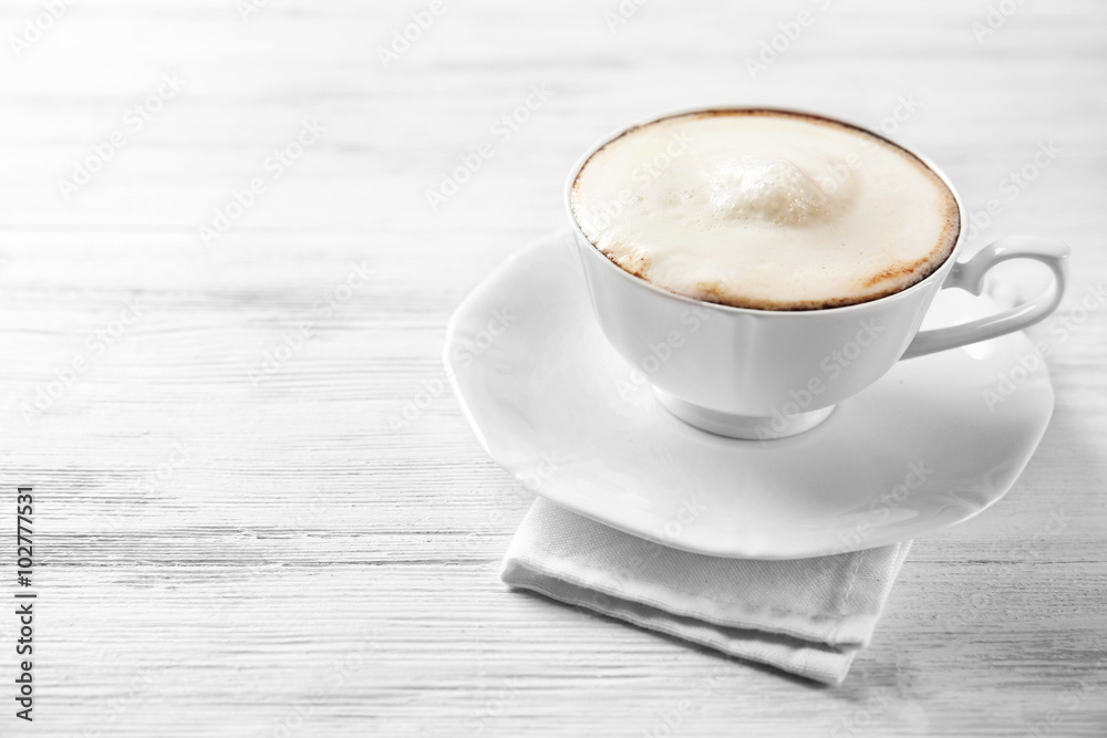Cup of cappuccino with frost on light wooden table