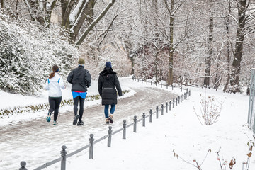 people walking and running by the river in the snow