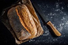 Fresh Bread And Knife On A Black Background With Copy Space.