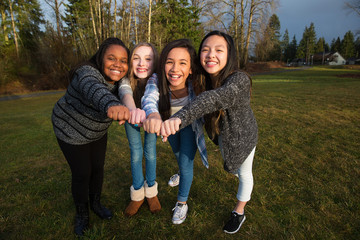 Wall Mural - Group of four kids making a unified fist to demonstrate girl pow