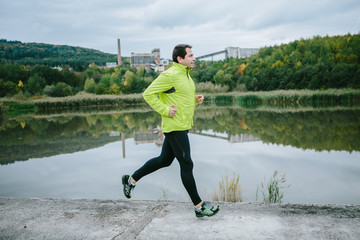 Man at the lake running on conrete path