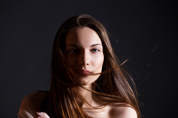 Portrait of beautiful brunette woman with natural look and without makeup on black background