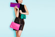 © MoustacheGirl - Woman holding many colorful bags. Isolated on light blue. Shopping. Fashion image.