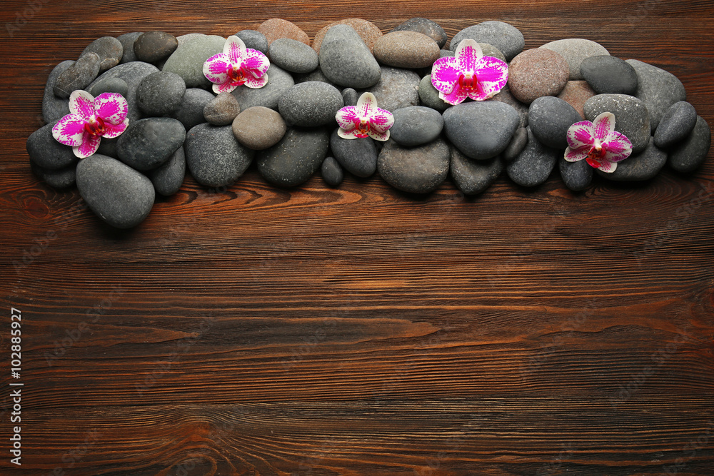 Spa stones and orchid on wooden background