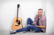 © Africa Studio - Young musician with guitar on light wall background