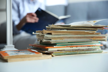 Poster - Pile of old books on white table in the room. Focus on books and blurred background